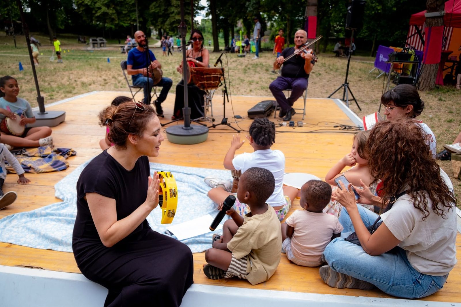 Des enfants chantent au micro avec les musiciens lors d'une restitution en plein air